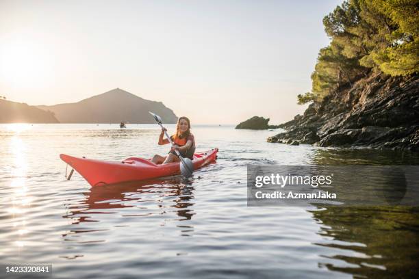 kayakra femenina remando fuera de la costa brava en la madrugada - borde del agua fotografías e imágenes de stock