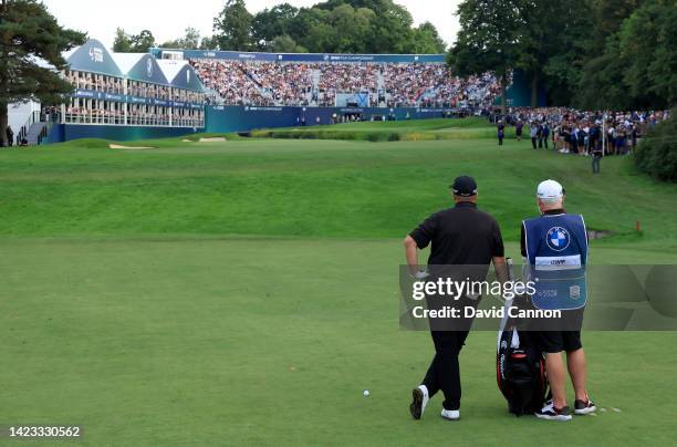 Shane Lowry of Ireland waits to play his second shot on the 18th hole with his caddie Bo Martin during the final round on day four of the BMW PGA...