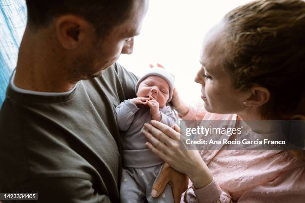 new parents holding their newborn baby - new baby fotografías e imágenes de stock