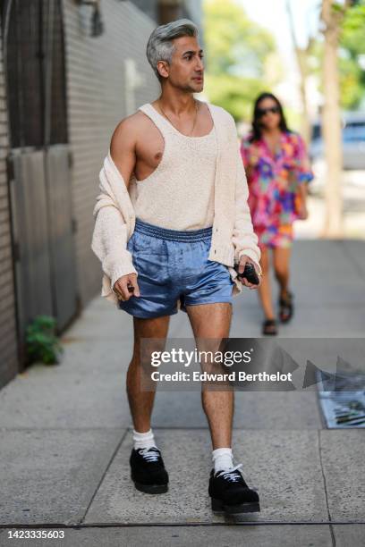 Guest wears a beige wool tank-top, a matching beige wool cardigan, blue satin shorts, white socks, black suede shoes, outside Altuzarra, during New...