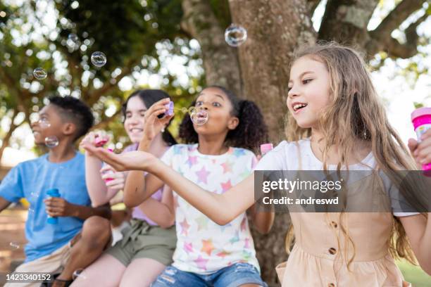 gruppo di bambini che giocano con la bolla di sapone - bubble wand foto e immagini stock