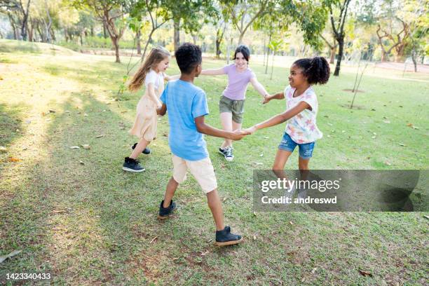pequeño grupo de niños jugando en el parque público - jugar fotografías e imágenes de stock