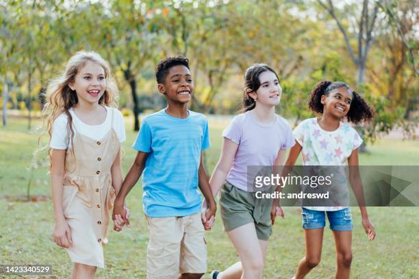 gruppo di bambini che camminano mano nella mano nel parco pubblico - solo bambini foto e immagini stock