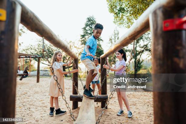 niños jugando en el patio de juegos - play fotografías e imágenes de stock