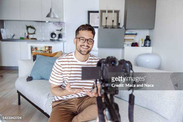 young smiling man recording vlog and talking - tevreden stockfoto's en -beelden