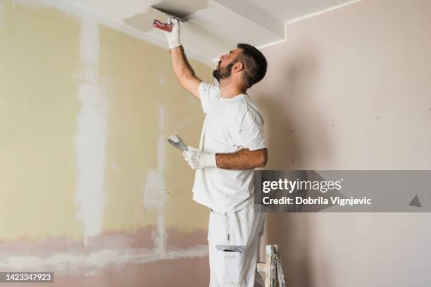 house painter painting ceiling - plaster construction material stock pictures, royalty-free photos & images