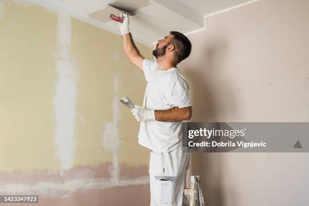 house painter painting ceiling - plasterer stock pictures, royalty-free photos & images