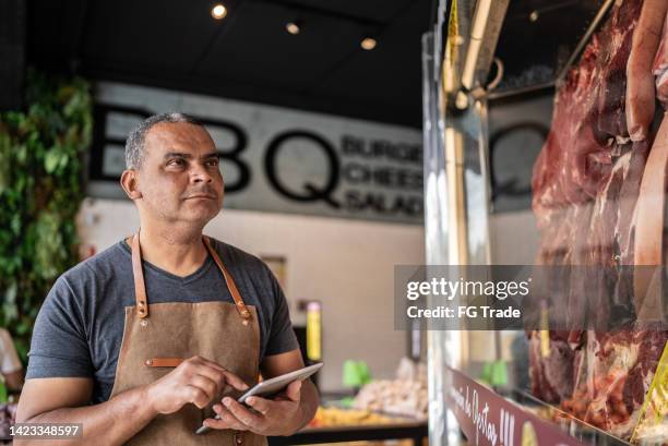 imprenditore con tablet digitale che fa l'inventario in una macelleria - butcher foto e immagini stock