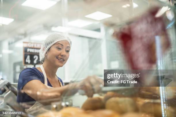 employee getting some bread to customer in a bakery - supermarket bread stockfoto's en -beelden