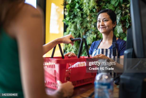 cashier checking out groceries in a supermarket - convenience store counter stockfoto's en -beelden