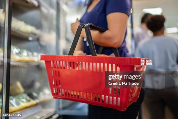 frau kauft lebensmittel im supermarkt - einkaufskorb stock-fotos und bilder