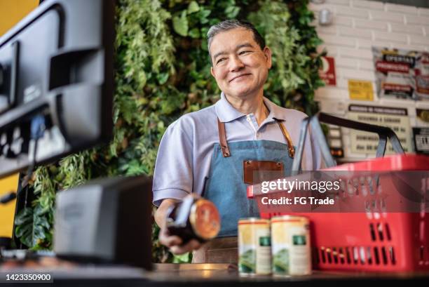 cashier checking out groceries in a supermarket - convenience store counter stockfoto's en -beelden