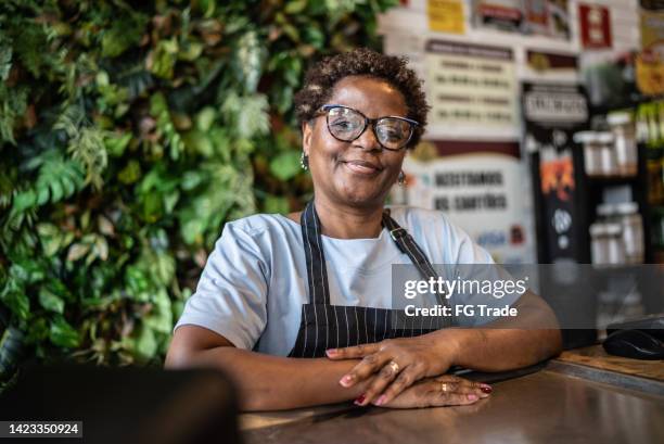 portrait of a senior woman cashier working in a market - convenience store counter stockfoto's en -beelden