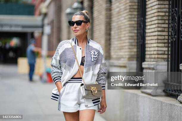 Olga Ferrara wears black sunglasses, a black lace print pattern bra underwear, a black and white checkered print pattern / silver leather / white...