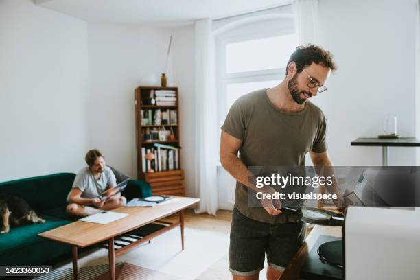 male couple with a dog listening vinyl records at home - gay men pic stock pictures, royalty-free photos & images