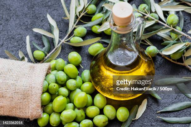 high angle view of oil in bottle with leaves on table - vegetable oil stock pictures, royalty-free photos & images