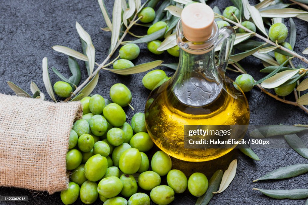 High angle view of oil in bottle with leaves on table