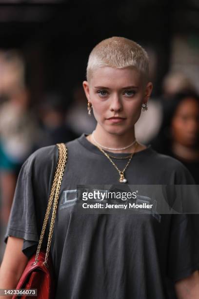 Model Maike Inga seen wearing silver and gold earrings, a white pearls necklace, gold necklaces, a gray t-shirt from Diesel, a red shiny leather...
