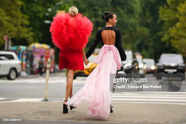 Leonie Hanne wears gold earrings, a red short dress with oversized ruffled tulle shoulder, a gold Juste Un Clou bracelet from Cartier, a gold and...