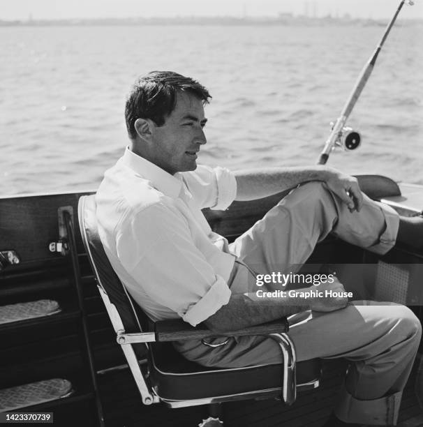 American actor Gregory Peck sits in a deep sea fishing chair and waits for the rented 35-foot vessel to arrive at the fishing grounds, at sea, 28th...