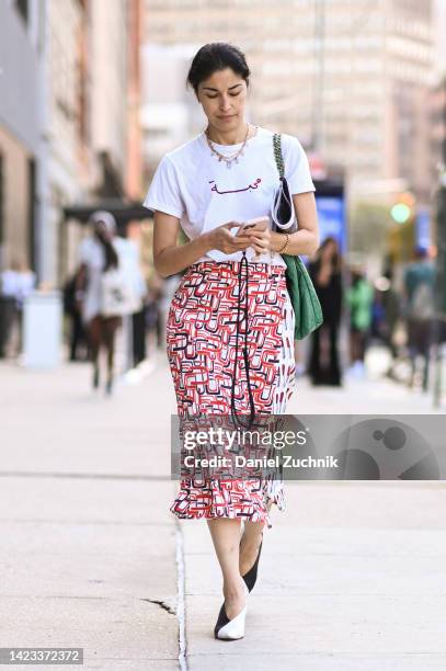 Caroline Issa is seen wearing a white t-shirt, red, white graphic skirt and black and white heels outside the Veronica Beard show during New York...