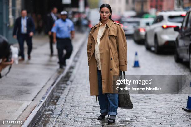 Fashion week guest seen wearing a beige trenchcoat, beige shirt, denim jeans, black boots and a wild leather bag outside Khaite during New York...