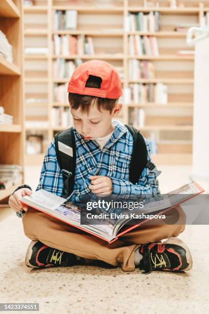 child in school library. kids read books. little boy reading and studying - comic book fotografías e imágenes de stock