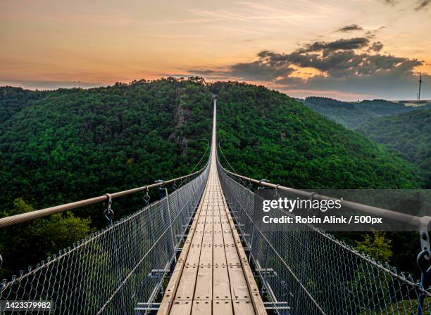 empty footbridge against sky during sunset - rope bridge stock pictures, royalty-free photos & images