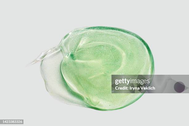 green color smears of gel, face serum or essential oil, shampoo, soap with oxygen aqua bubbles on gray color background. - aloe vera gel stock-fotos und bilder