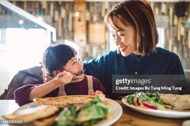 mom & daughter enjoying meal in the restaurant - children restaurant stock pictures, royalty-free photos & images