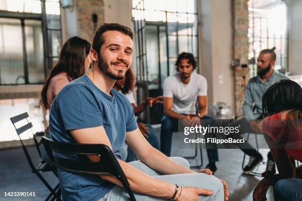 retrato de un hombre mirando a la cámara durante una sesión de terapia de grupo - alivio fotografías e imágenes de stock