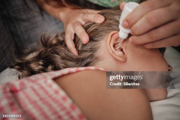 mother putting drops in little girl's ear - ohrenschmerzen stock-fotos und bilder