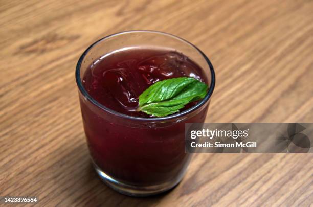 glass of mixed berry (raspberry, blackberry, blueberry) shrub, an acidulated (with balsamic vinegar) mineral water drink, with ice cubes and a mint leaf - brambleberry stock pictures, royalty-free photos & images