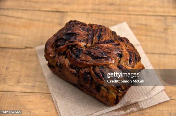 chocolate babka loaf on a paper napkin on a wooden cafe table - sweet bread fotografías e imágenes de stock