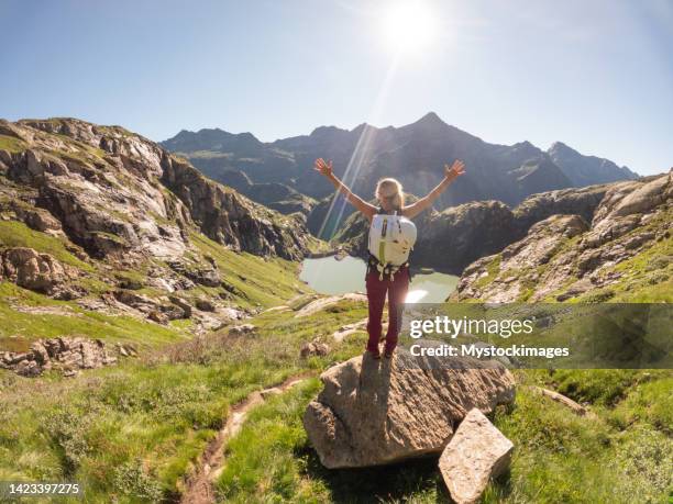 young woman hiking in a beautiful alpine scenery in summer walking in the swiss alps enjoying nature and the outdoors - swiss alps summer stock pictures, royalty-free photos & images