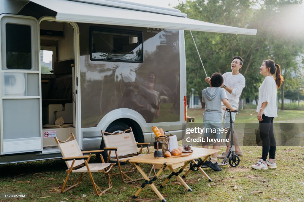 Familia asiática china instalando toldo en una caravana
