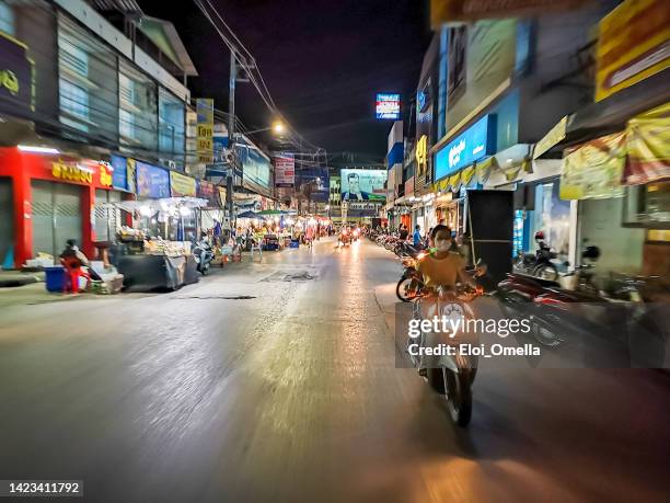 woman riding a motorcycle in the streets of chiang rai at night - chiang rai province stock pictures, royalty-free photos & images