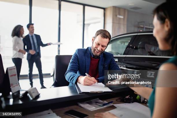 l'uomo sta acquistando / noleggiando una nuova auto e firmando un contratto - venditore di automobili foto e immagini stock