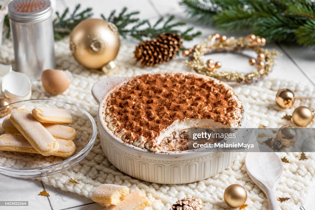 Festive Christmas Dessert Tiramisu sponge cake in bright rustic kitchen with golden Christmas Ornaments
