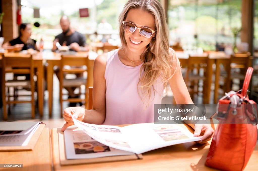 Happy young woman looking at a menu at a restaurant
