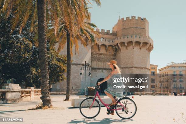 woman ridding bicycle by torres de serranos city gate of valencia spain - provinsen valencia bildbanksfoton och bilder