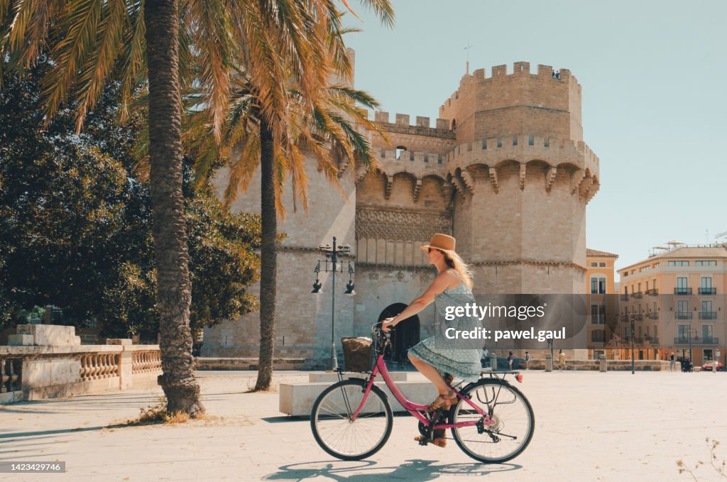 Woman ridding bicycle by Torres de Serranos city gate of Valencia Spain