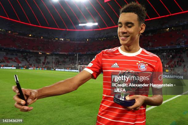 Jamal Musiala of Bayern Munich takes a selfie with the UEFA Champions League PlayStation Player of the Match award following their sides victory in...