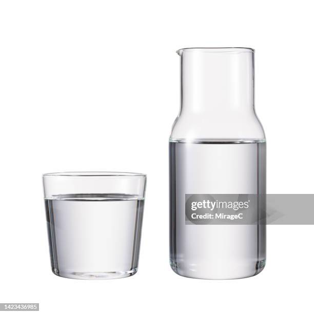glass water pitcher with drinking glass full of water isolated on white - jarra recipiente - fotografias e filmes do acervo