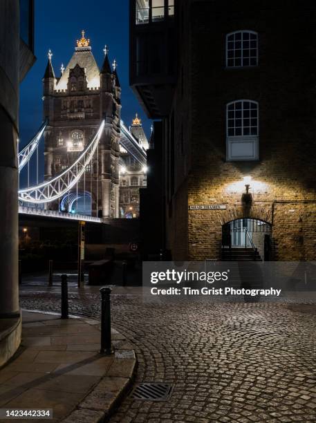 tower bridge and the cobblestone street of shad thames, london at night - london landmark ストックフォトと画像