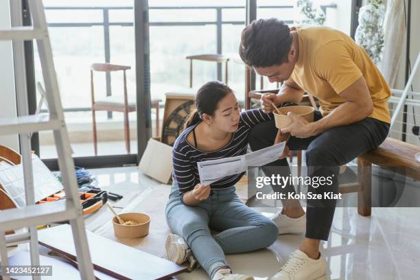 home ownership - a young couple reading a manual in the midst of remodeling their home by doing it themselves - malay lover stock pictures, royalty-free photos & images