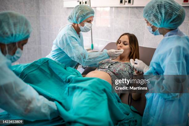 in the hospital woman giving birth support, obstetricians assisting. modern delivery ward with professional midwives - woman giving birth 個照片及圖片檔