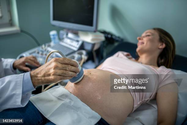 arzt, der ultraschall an einer schwangeren frau durchführt - baby in womb stock-fotos und bilder