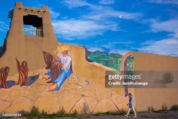taos, nm: man walking past mural at dusk, downtown taos - adobe creative cloud stock pictures, royalty-free photos & images