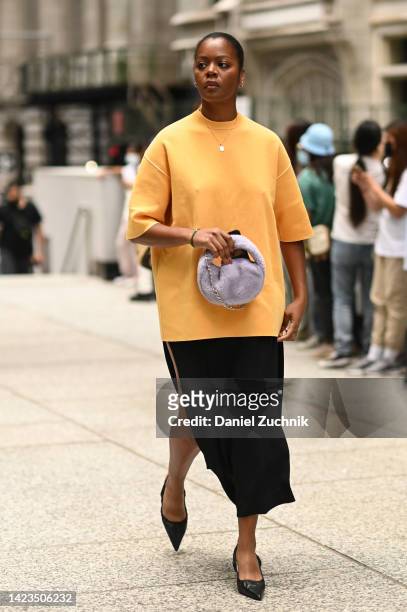 Guest is seen wearing an orange top, black skirt, black flats and purple faux fur bag outside the Peter Do show during New York Fashion Week S/S 2023...